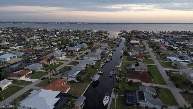 aerial view at dusk featuring a water view