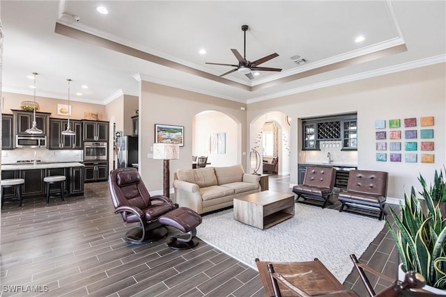 living room featuring a raised ceiling and ornamental molding