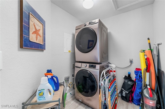 laundry area with light hardwood / wood-style floors and stacked washer / dryer