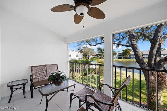 sunroom with ceiling fan, a water view, and lofted ceiling