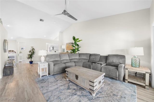 living room with ceiling fan, light hardwood / wood-style floors, and vaulted ceiling