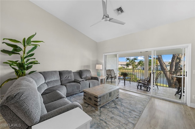 living room with ceiling fan, hardwood / wood-style floors, a water view, and vaulted ceiling