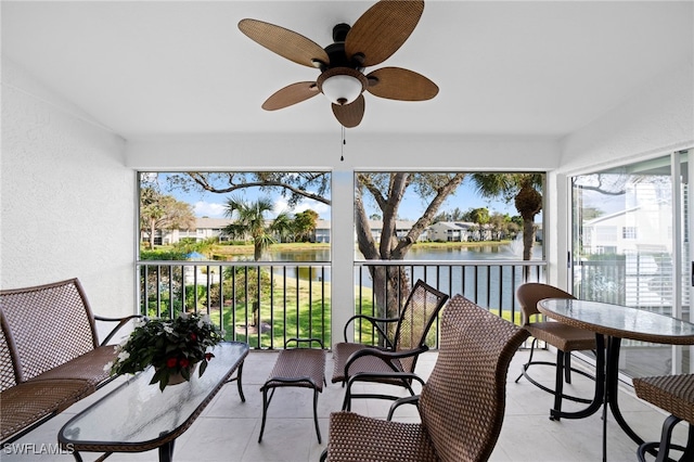 sunroom / solarium with ceiling fan and a water view