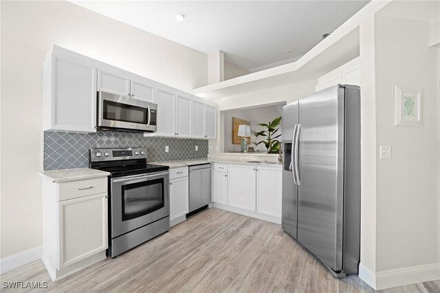 13120 Castle Harbour Dr Unit N4, Naples, FL 34110 - kitchen with appliances with stainless steel finishes, light countertops, decorative backsplash, white cabinetry, and light wood-style flooring
