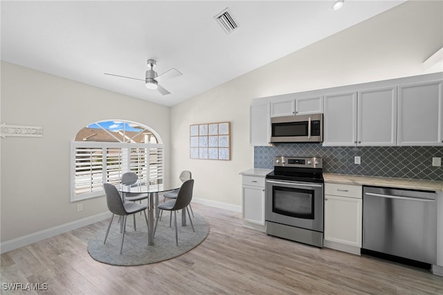 kitchen featuring white cabinets, ceiling fan, stainless steel appliances, and vaulted ceiling