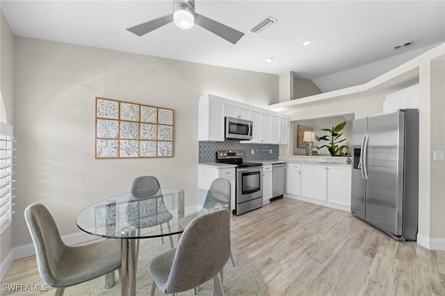 kitchen featuring white cabinetry, ceiling fan, stainless steel appliances, backsplash, and vaulted ceiling