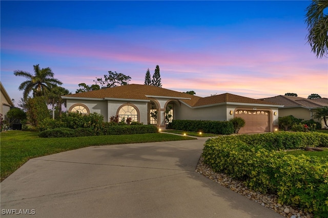 mediterranean / spanish-style home with a garage and a lawn