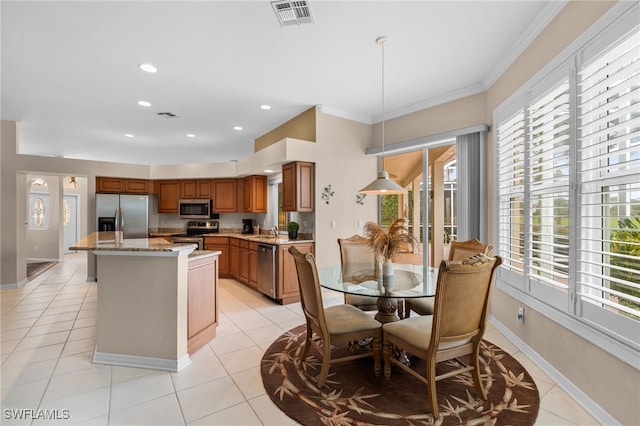 kitchen with light stone countertops, stainless steel appliances, pendant lighting, light tile patterned floors, and a center island