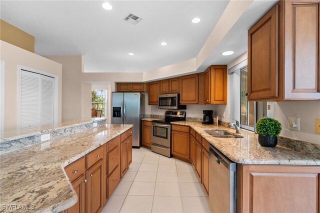 kitchen featuring light stone countertops, appliances with stainless steel finishes, light tile patterned floors, and sink