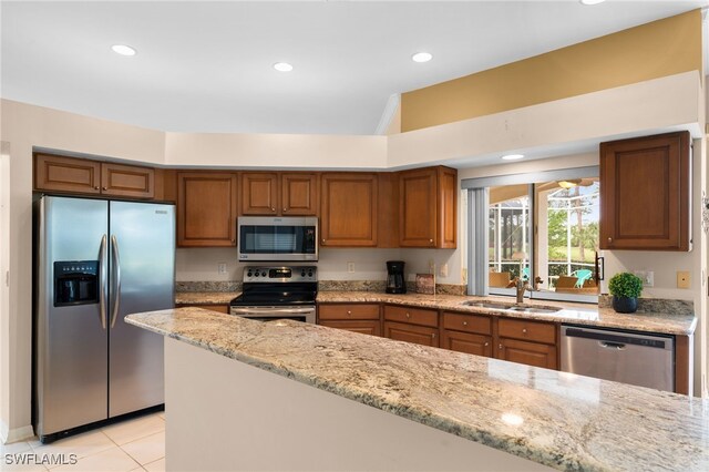 kitchen featuring light tile patterned floors, stainless steel appliances, light stone counters, and sink