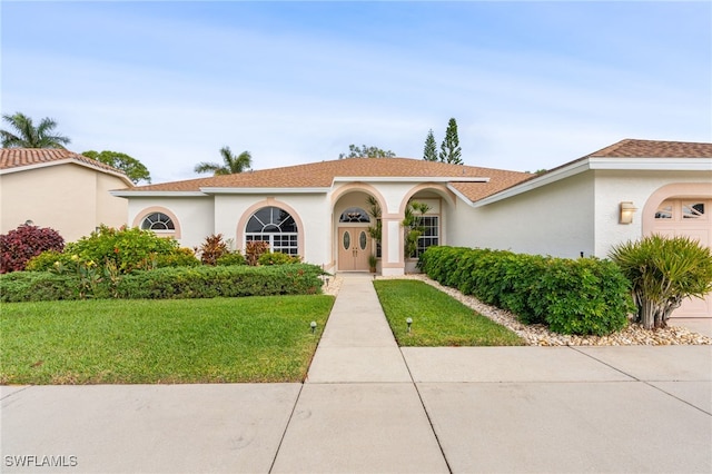 mediterranean / spanish-style home featuring a garage and a front lawn