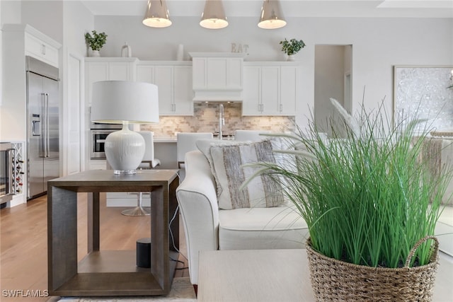 interior space with white cabinetry, stainless steel appliances, backsplash, and decorative light fixtures