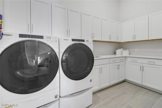 washroom with light tile patterned floors, separate washer and dryer, and cabinet space