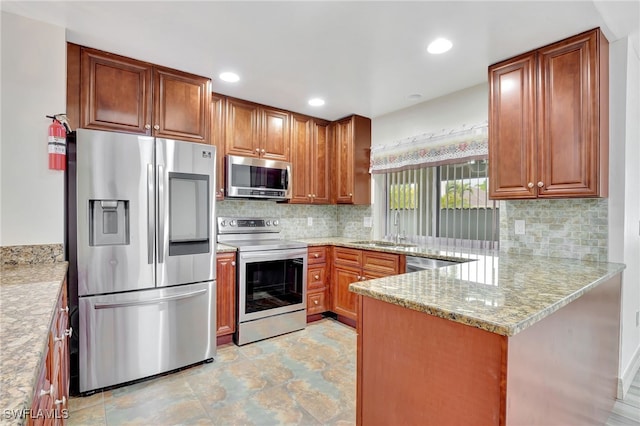 kitchen with kitchen peninsula, appliances with stainless steel finishes, decorative backsplash, light stone countertops, and sink