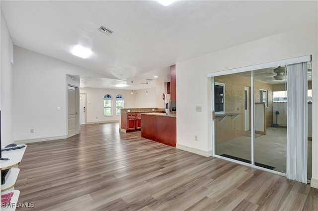 interior space featuring kitchen peninsula, lofted ceiling, and light wood-type flooring