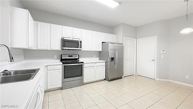 kitchen featuring hanging light fixtures, sink, appliances with stainless steel finishes, light tile patterned flooring, and white cabinetry