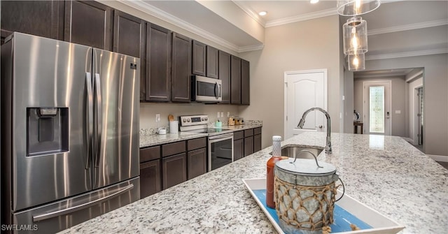 kitchen with dark brown cabinetry, sink, light stone counters, pendant lighting, and appliances with stainless steel finishes