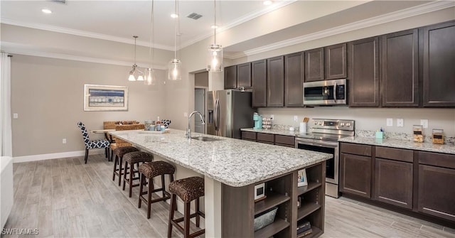 kitchen with pendant lighting, a breakfast bar, a kitchen island with sink, sink, and stainless steel appliances