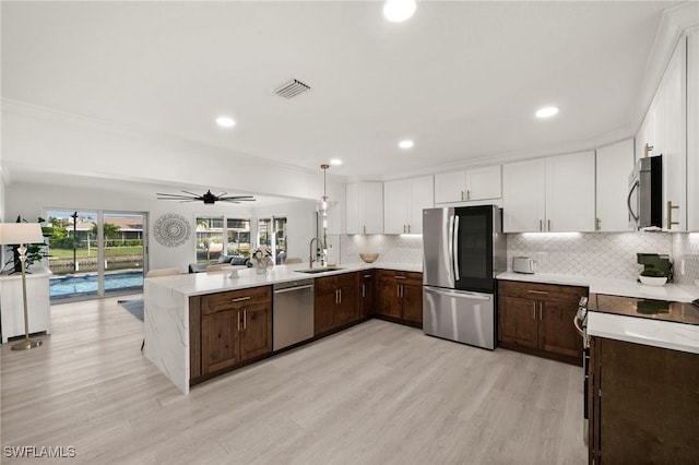 kitchen with white cabinetry, ceiling fan, sink, hanging light fixtures, and appliances with stainless steel finishes