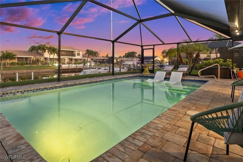 pool at dusk featuring a patio and glass enclosure