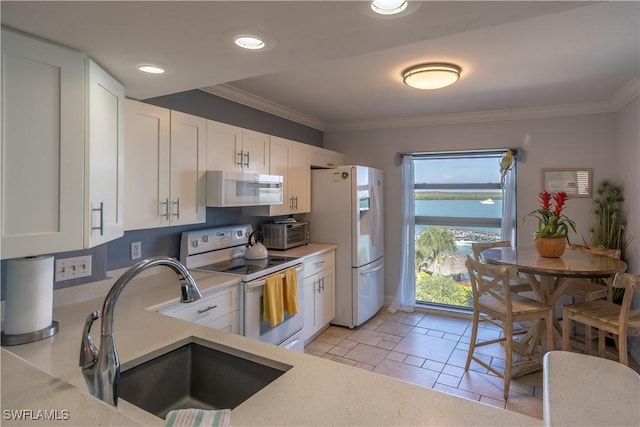 kitchen featuring white appliances, a water view, white cabinetry, and sink