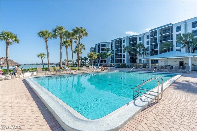 view of swimming pool featuring a water view and a patio