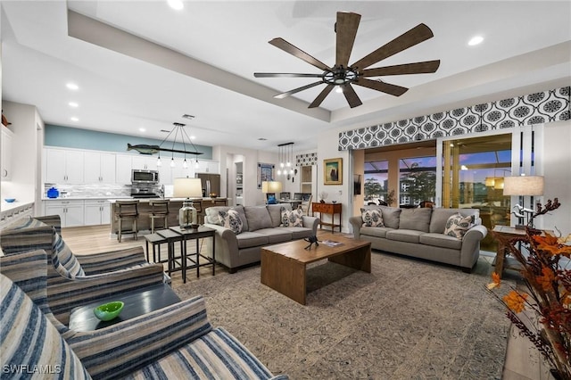 living room with a tray ceiling and ceiling fan