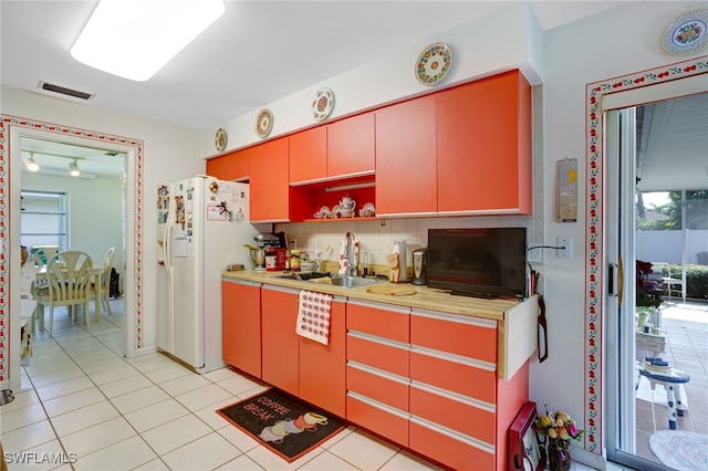 kitchen featuring decorative backsplash, light tile patterned flooring, white refrigerator with ice dispenser, and sink