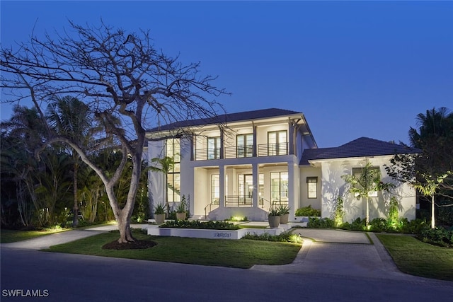 view of front of home with a balcony and a front yard