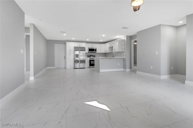 unfurnished living room with recessed lighting, marble finish floor, a sink, and baseboards