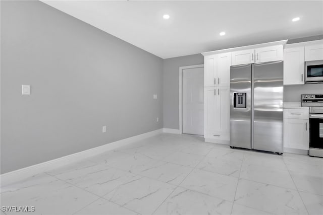 kitchen featuring appliances with stainless steel finishes, light countertops, marble finish floor, and white cabinets