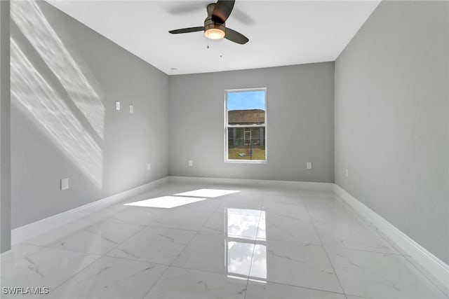 unfurnished room featuring ceiling fan, marble finish floor, and baseboards