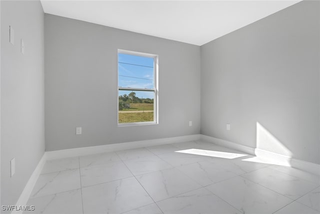 empty room featuring marble finish floor and baseboards