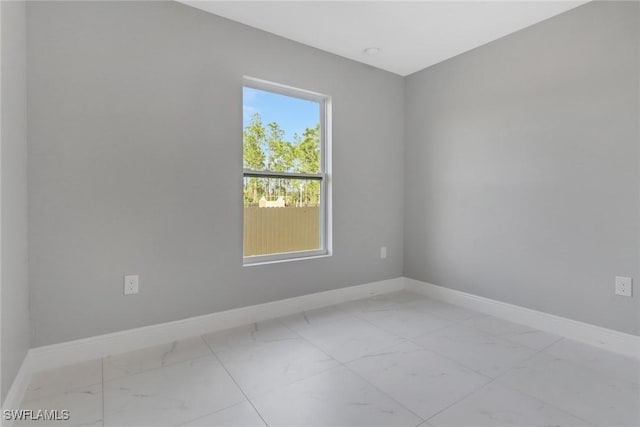 spare room featuring marble finish floor and baseboards