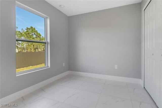 spare room with marble finish floor and baseboards