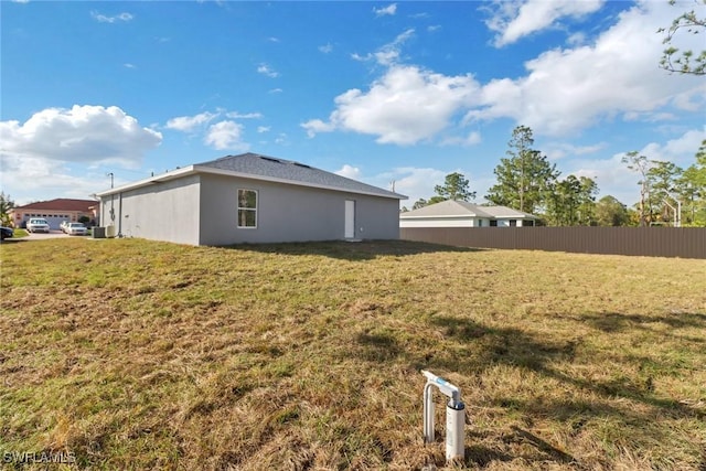 view of side of property featuring stucco siding, fence, and a yard