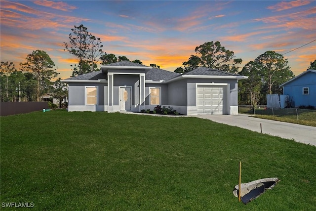 prairie-style home featuring a garage and a lawn