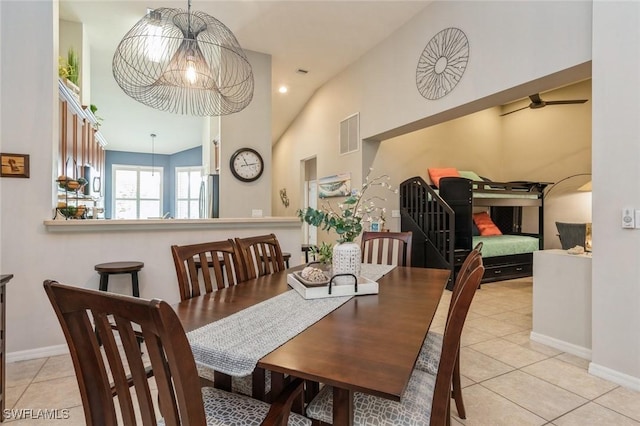 dining room featuring vaulted ceiling, light tile patterned floors, and ceiling fan with notable chandelier