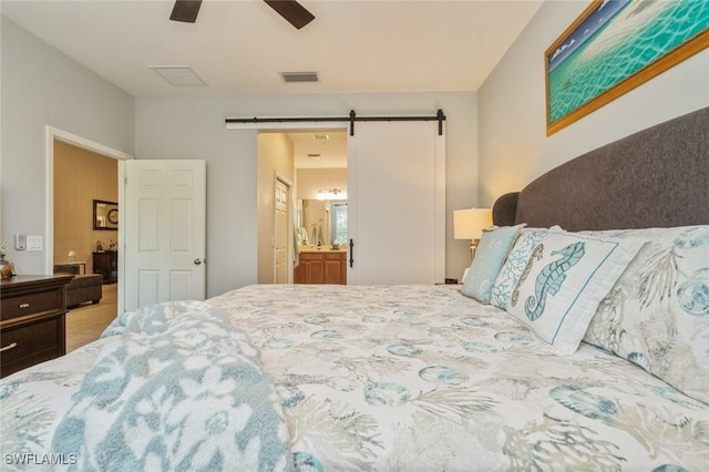 bedroom featuring connected bathroom, ceiling fan, and a barn door