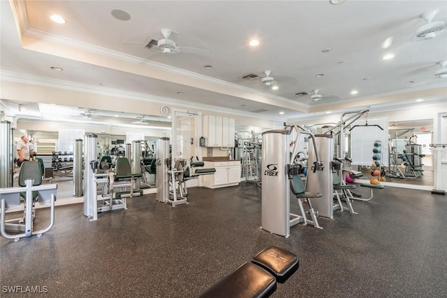 gym with ceiling fan, ornamental molding, and a tray ceiling