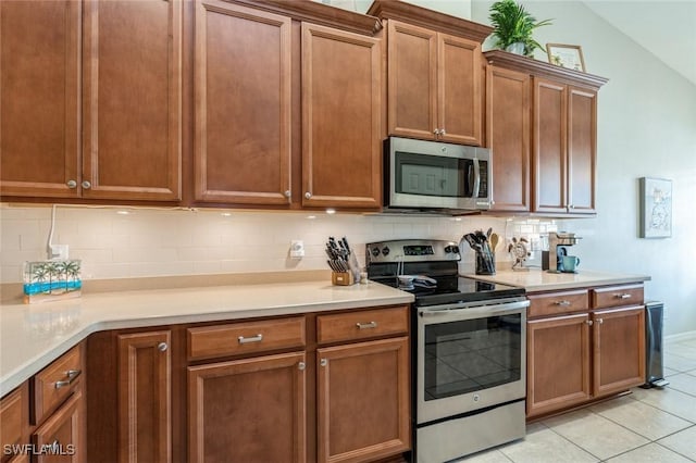 kitchen featuring lofted ceiling, light tile patterned flooring, tasteful backsplash, and stainless steel appliances