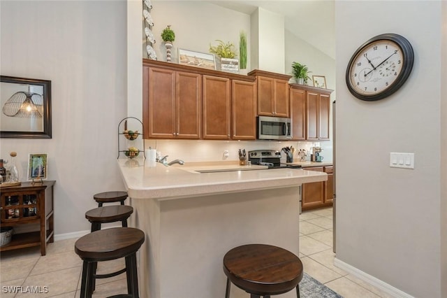 kitchen with a breakfast bar, appliances with stainless steel finishes, and light tile patterned flooring