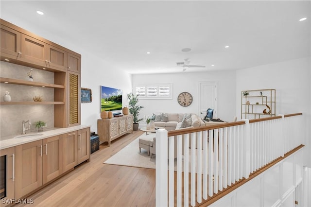 living room with light wood-type flooring, ceiling fan, and sink