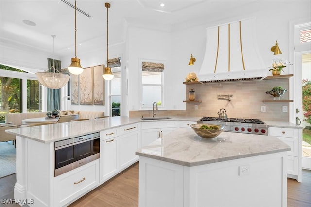 kitchen with white cabinets, sink, decorative backsplash, a kitchen island, and light stone counters