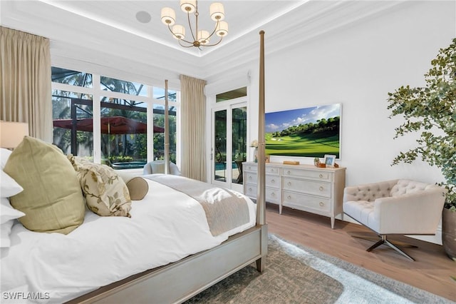 bedroom with hardwood / wood-style floors, a raised ceiling, and an inviting chandelier