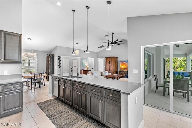 kitchen with sink, hanging light fixtures, light tile patterned floors, an island with sink, and dark brown cabinetry