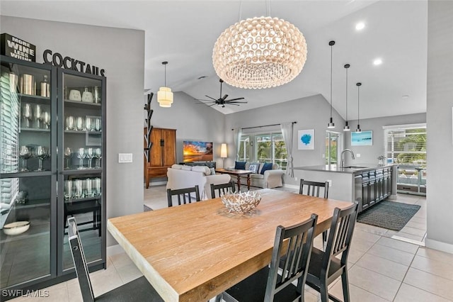 tiled dining room with ceiling fan with notable chandelier, vaulted ceiling, and sink