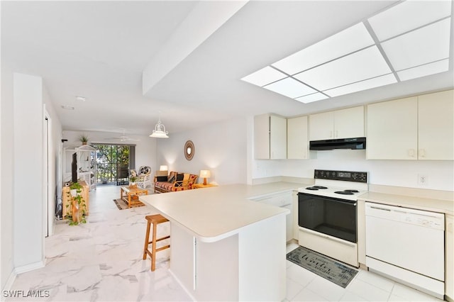 kitchen featuring kitchen peninsula, a kitchen breakfast bar, white appliances, ceiling fan, and decorative light fixtures