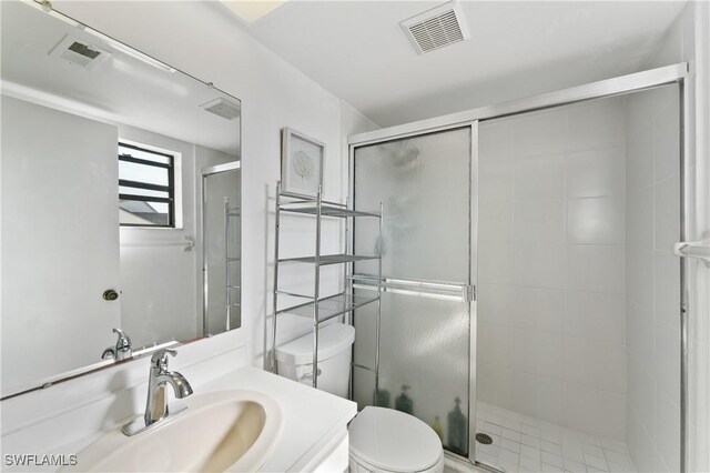 bathroom featuring an enclosed shower, vanity, and toilet