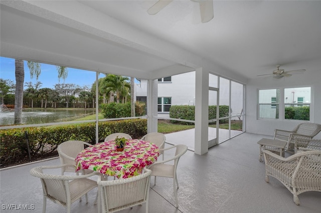 sunroom featuring ceiling fan and a water view